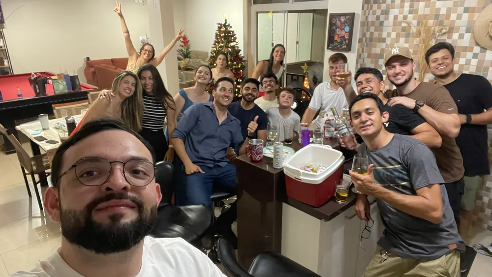 Grupo grande de amigos numa festa em casa, árvore de Natal ao fundo