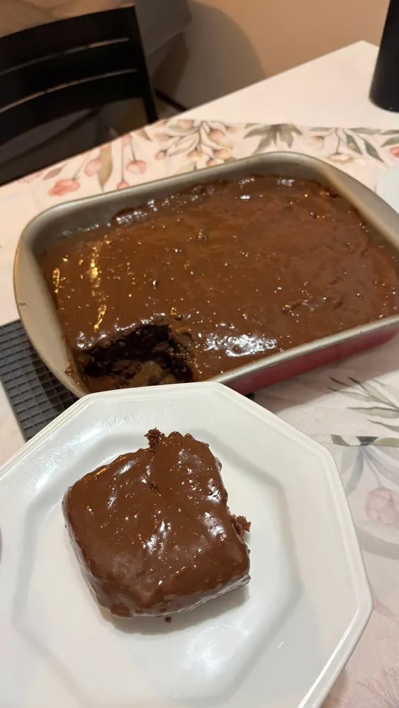 Bolo de chocolate na assadeira e um pedaço servido em prato branco