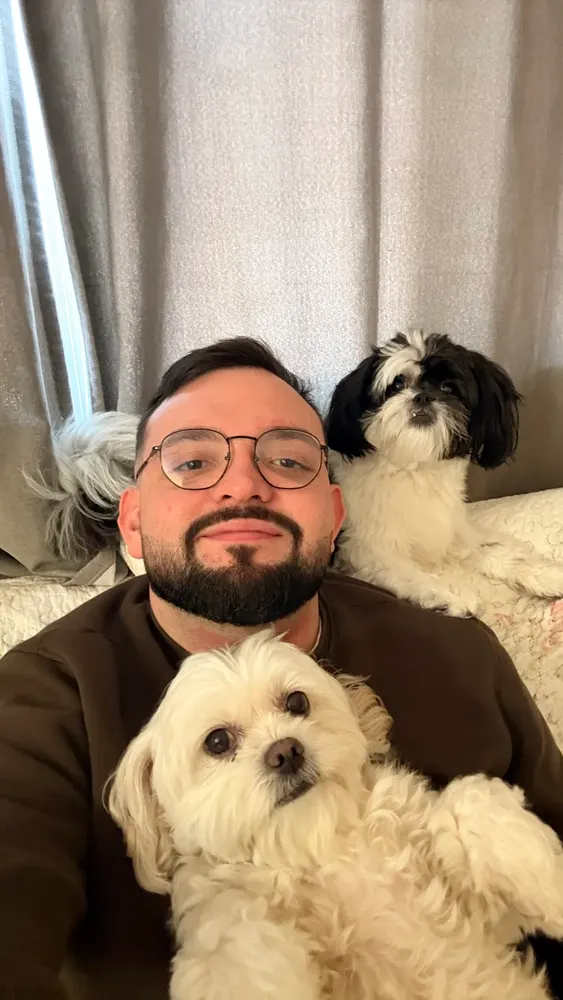 Selfie no sofá com cachorro branco no colo e outro preto e branco ao lado