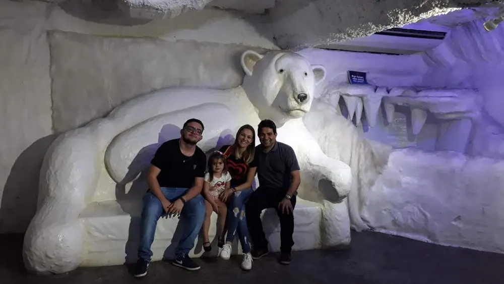 Quatro pessoas sentadas em escultura de urso polar num cenário de gelo