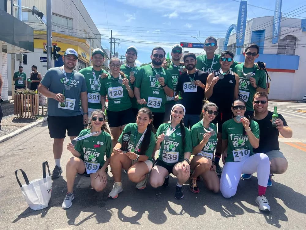 Grupo em camisetas verdes exibe medalhas de corrida na rua
