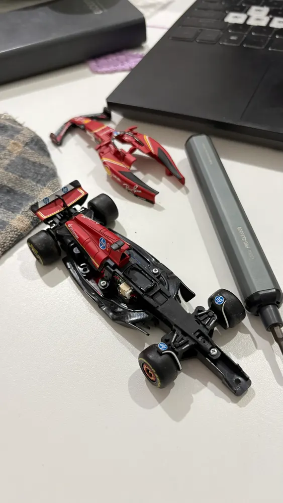 Miniatura de Fórmula 1 vermelha desmontada na mesa, ao lado de chave de fenda