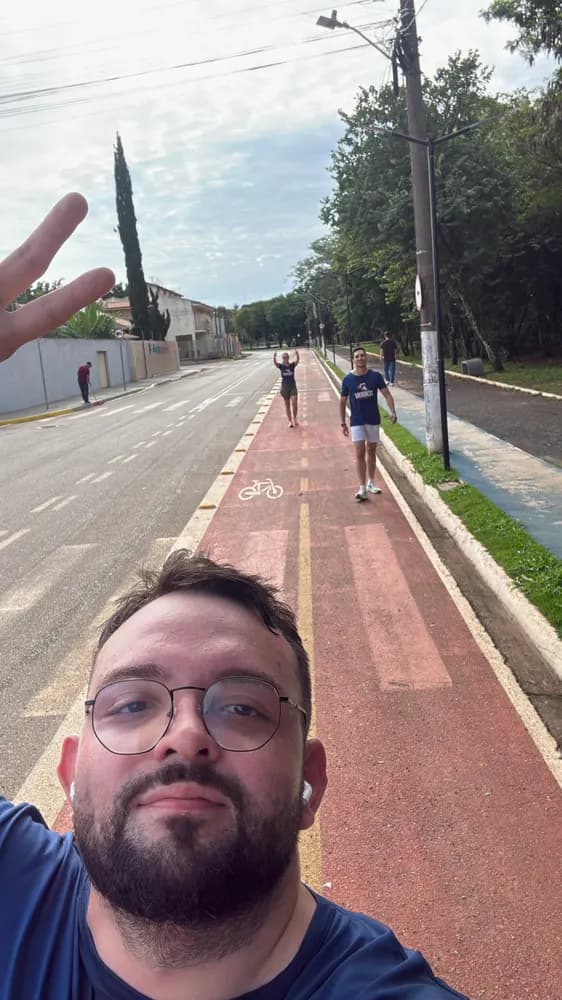Selfie numa ciclovia vermelha de avenida, com pessoas caminhando ao fundo
